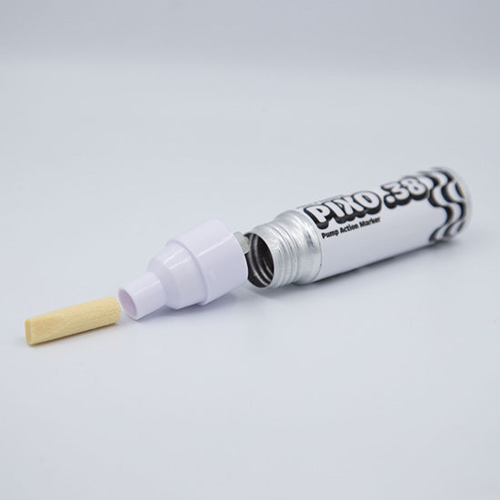 A pump-action marker pen shown open with the cap removed, revealing the internal plunger and a small beige felt tip. The barrel is white with black printed branding and text, photographed on a clean light gray background.