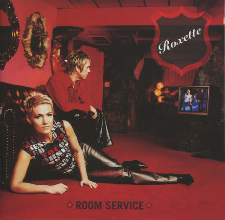 Roxette's 'Room Service' album cover, featuring two women in a red-lit room. One woman in a patterned top and black leather pants reclines on the red carpet in the foreground, while another woman in a red top and black leather pants sits behind her.