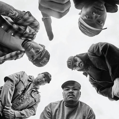 Black and white photo of six people standing in a circle with a neutral background
