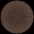 Brown circular object with text 'nothing is a field' on a black background