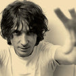 Black and white photo of a person with long hair, wearing a light-colored shirt.