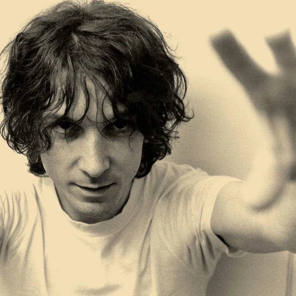 Black and white photo of a person with long hair, wearing a light-colored shirt.