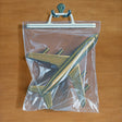 A clear plastic bag containing a gold-colored model airplane, displayed on a wooden surface.