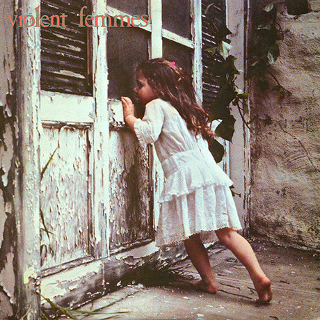 Album cover featuring a young child in a white dress standing next to a dilapidated door.
